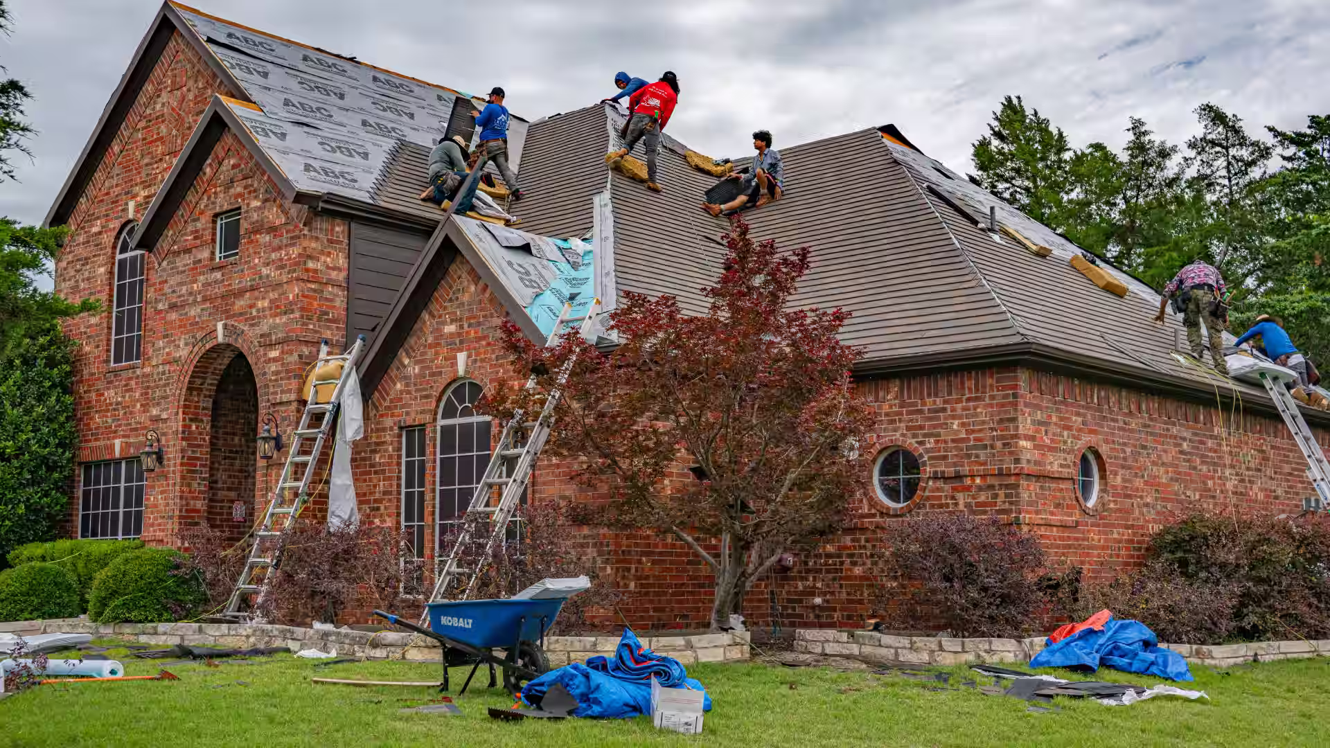 Roofing contractors fixing and replacing shingles on a house roof
