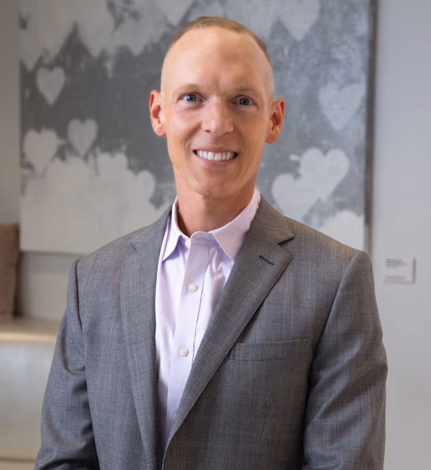 Dr. Siedhoff smiling at the camera in the lobby of medical practice, wearing grey suit.