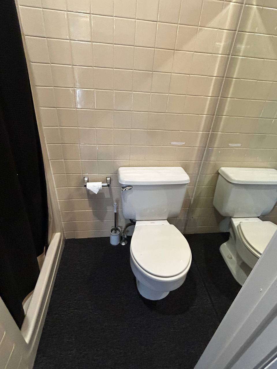Small bathroom with white toilet, beige wall tile and dark floor