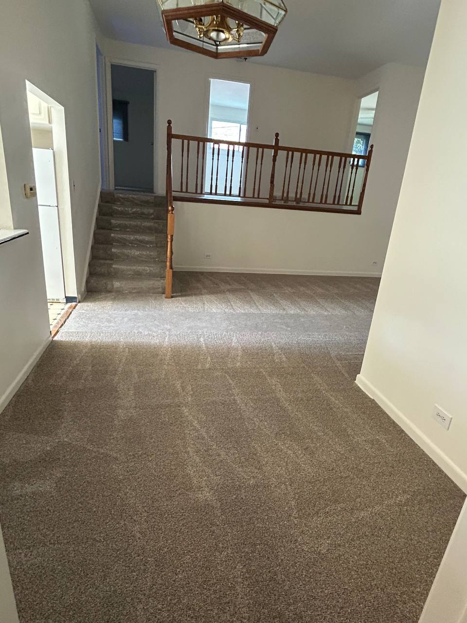 Carpeted split level entry with vacuum lines, stairs and wood railing