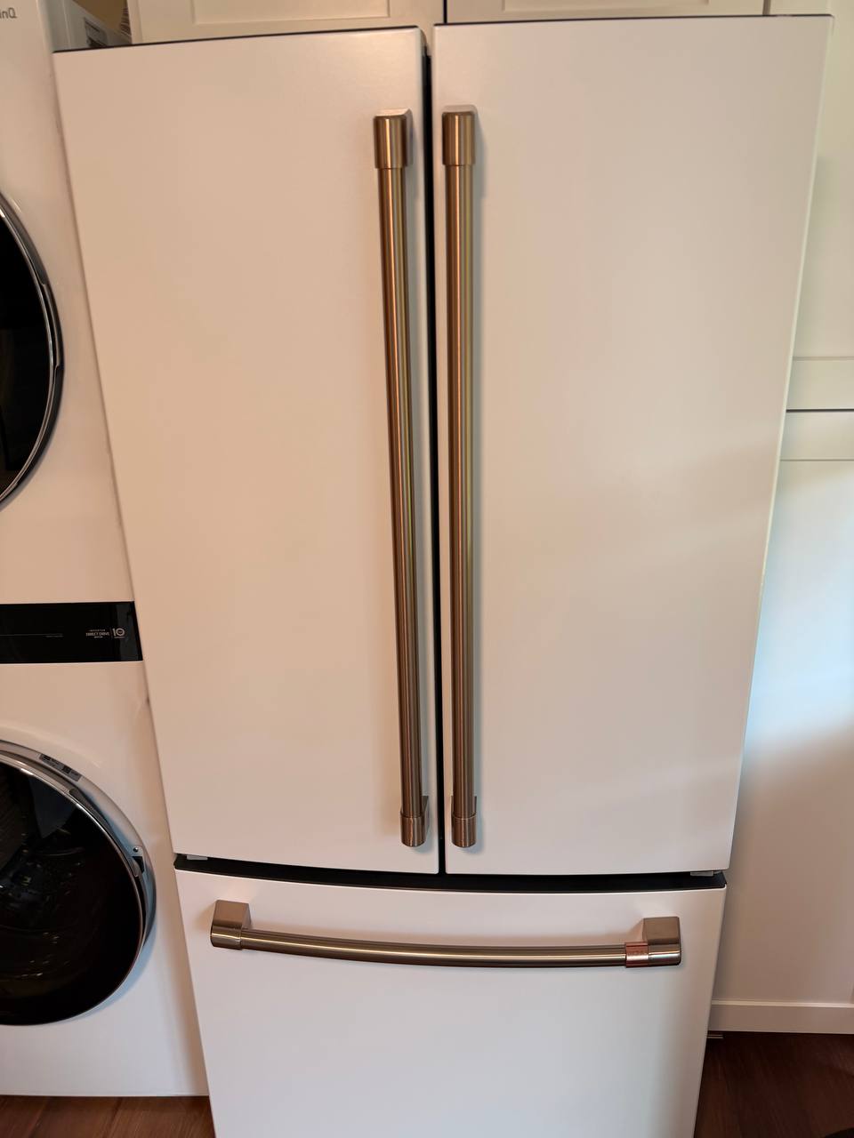 White refrigerator with brass handles next to a stacked washer dryer
