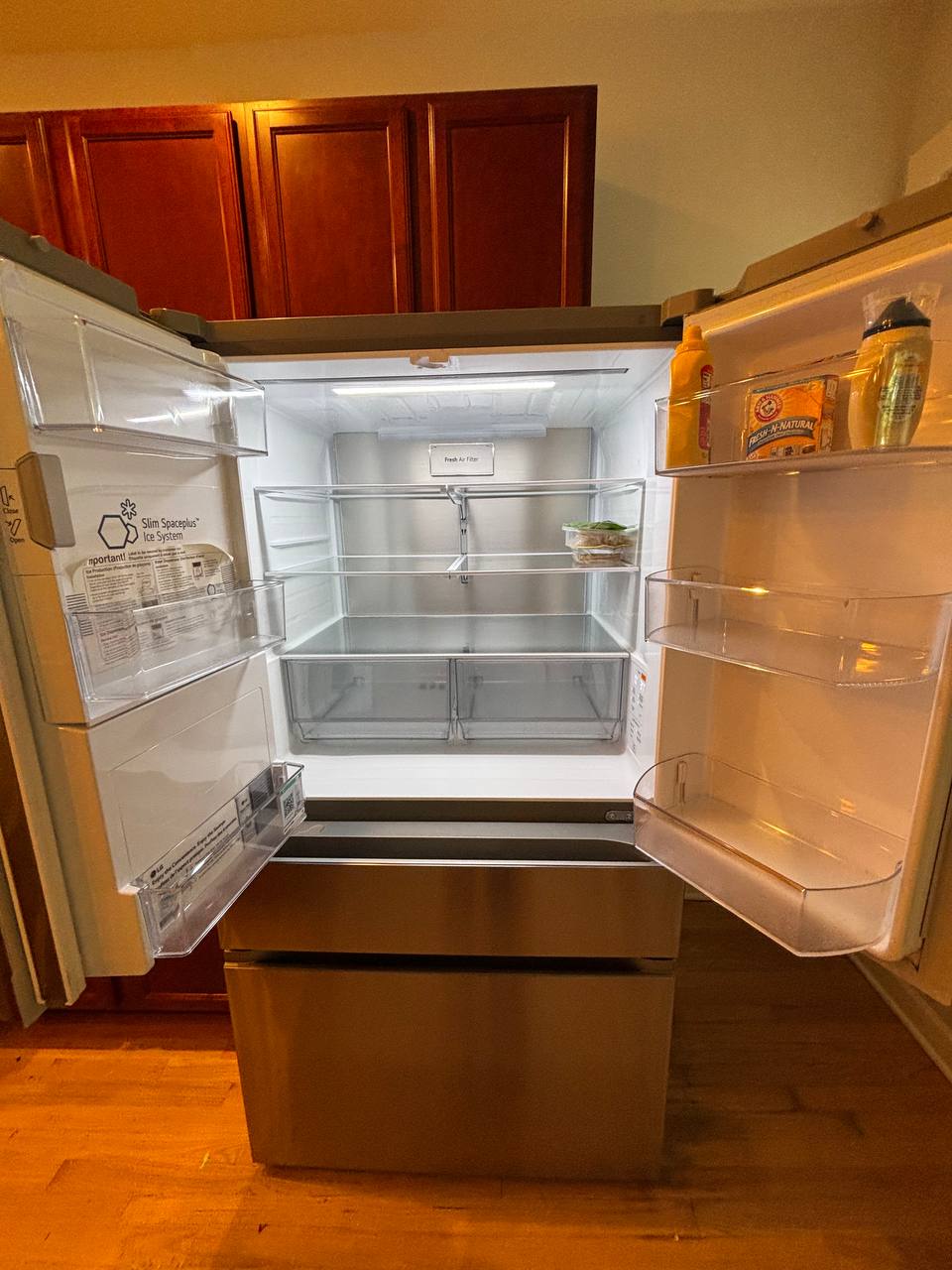 Open refrigerator with cleaned empty glass shelves and clear bins