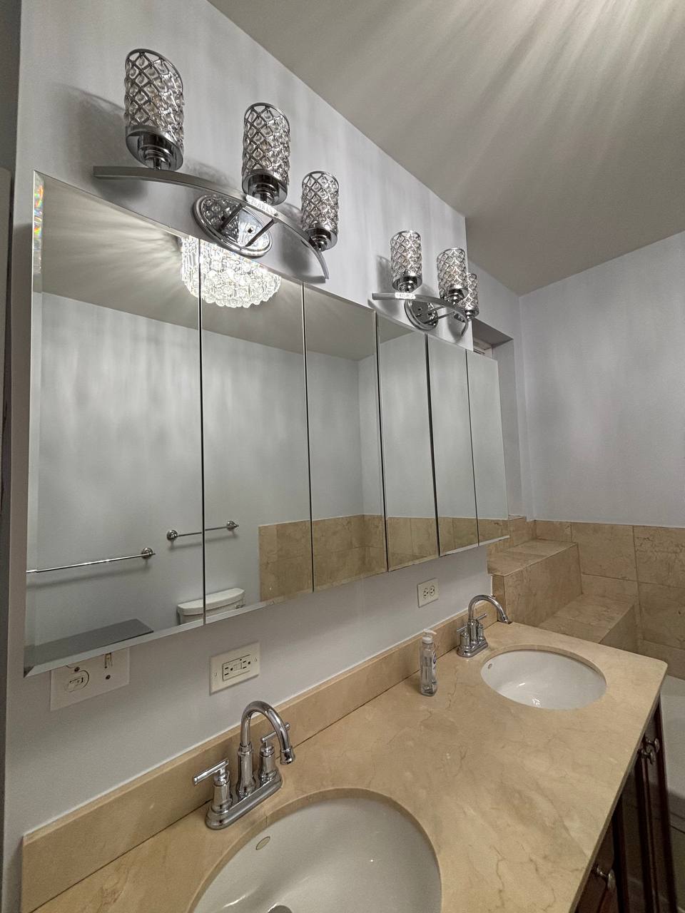 Double sink vanity with beige marble top and mirrored cabinets