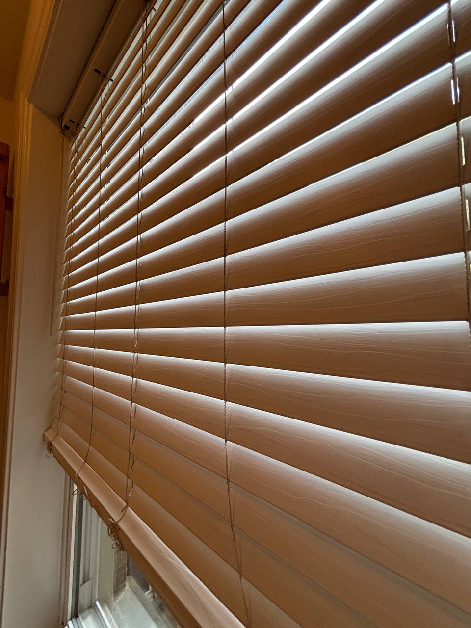 Close view of dusted wooden window blinds in a sunlit window