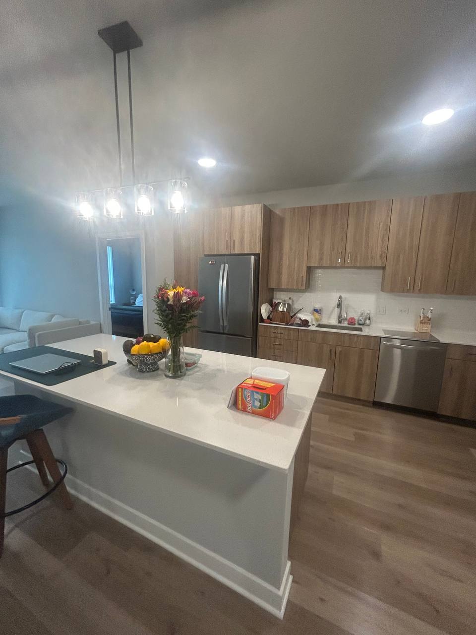 Kitchen island with flowers and fruit bowl facing wood cabinets and stainless fridge