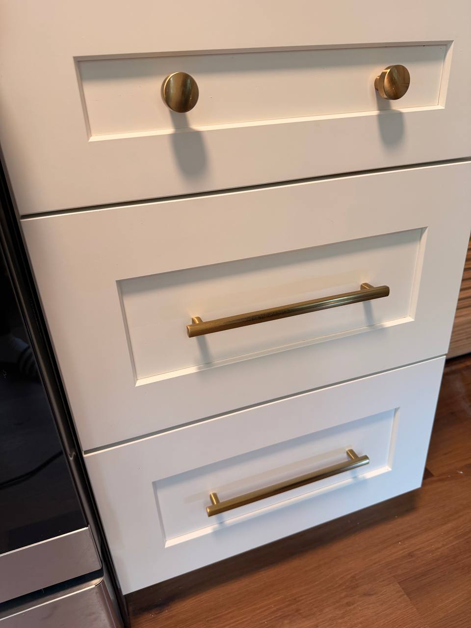 White kitchen drawers with brass knobs and bar pulls