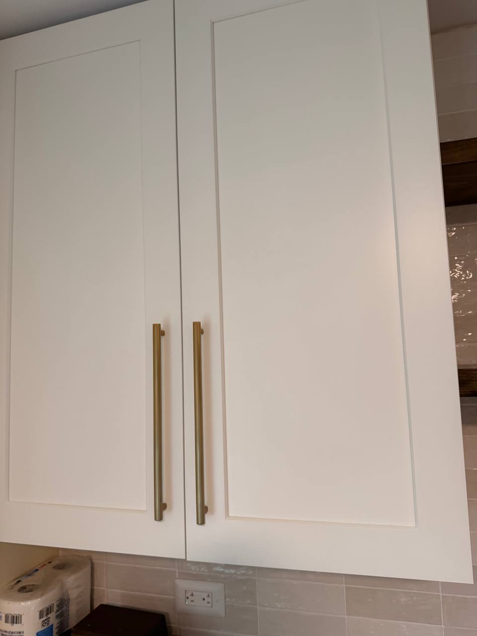 Two white cabinet doors with long brass handles
