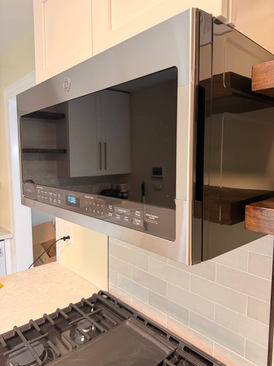 Stainless over-the-range microwave above a gas cooktop with tile backsplash