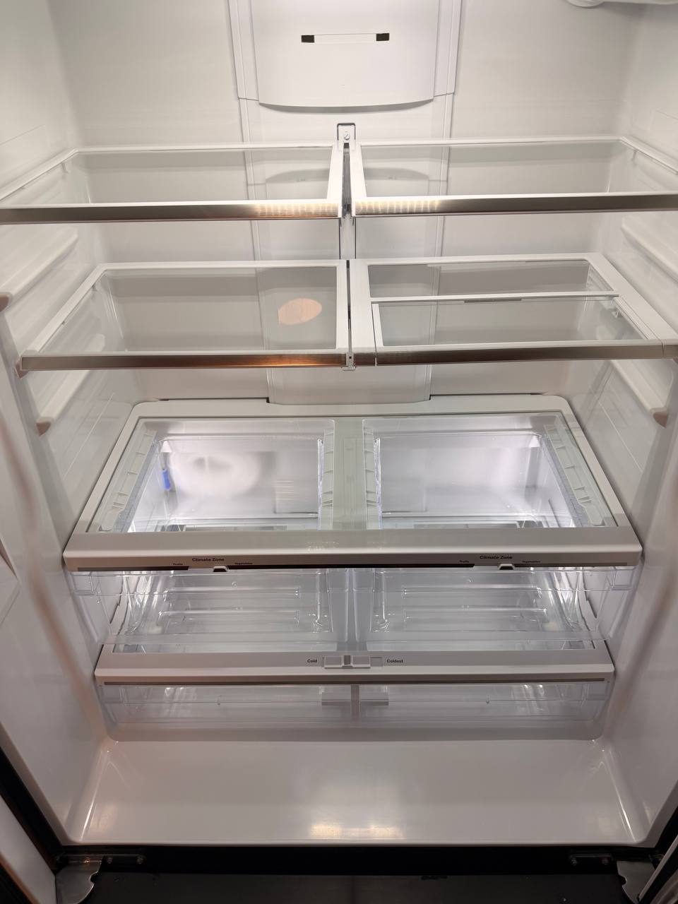 Empty refrigerator interior with glass shelves and clear drawers