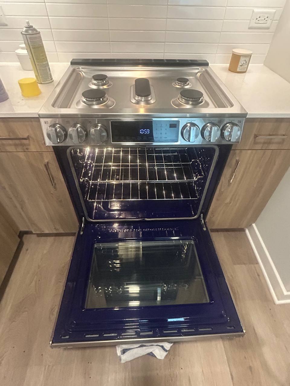Stainless gas range with oven door open showing clean racks