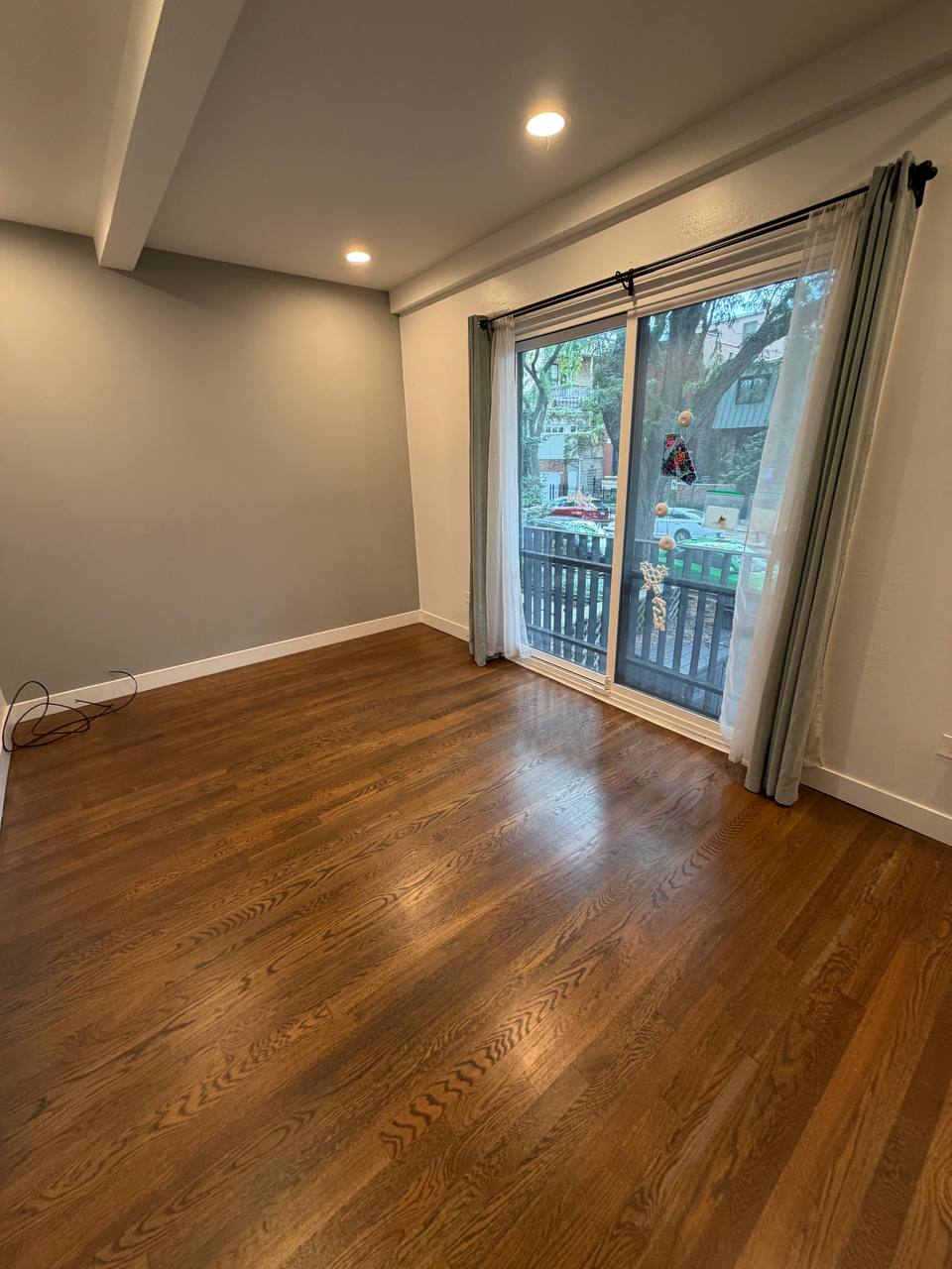 Empty room with dark hardwood floor and sliding door to a balcony