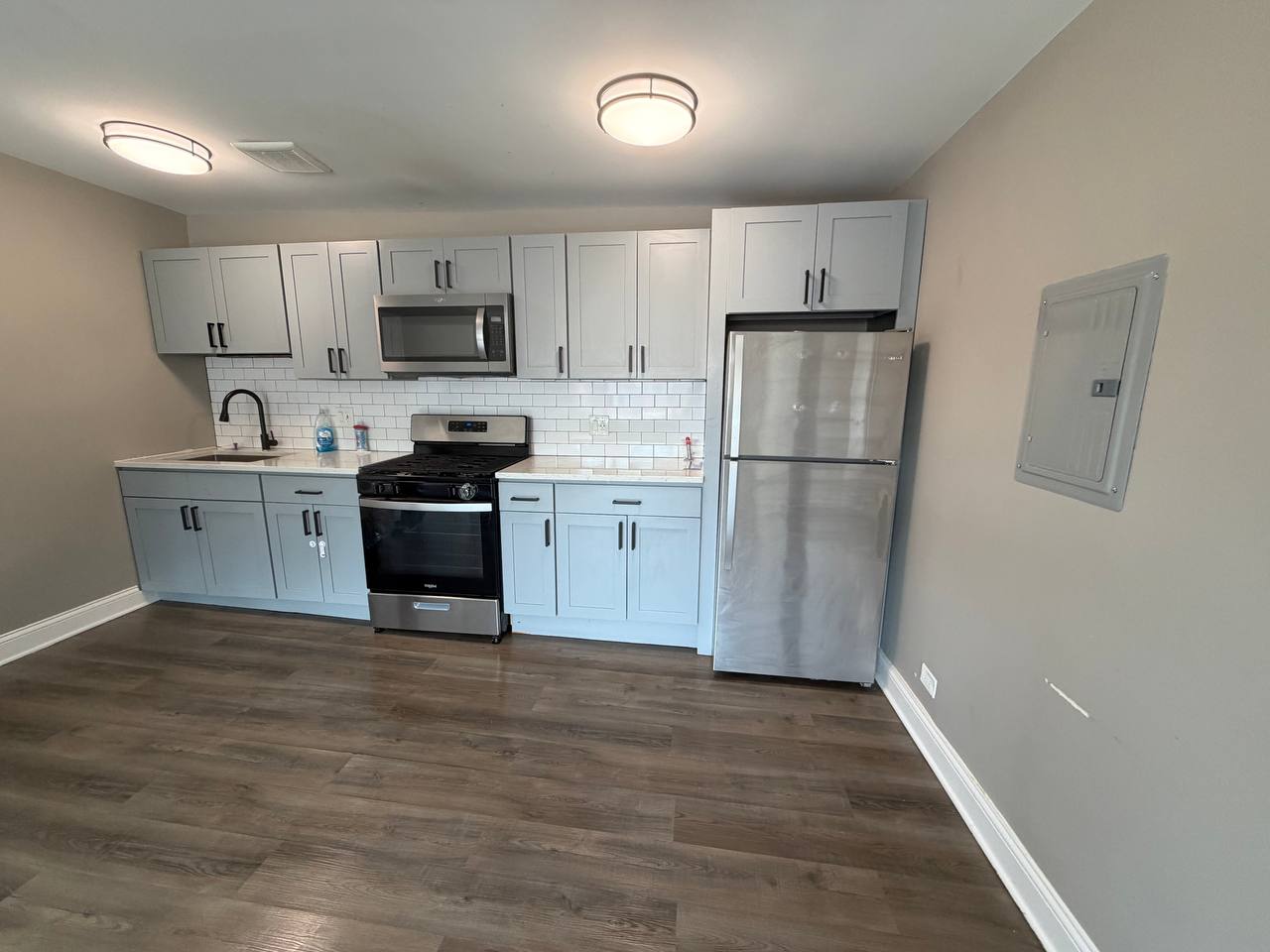 Gray kitchen with stainless fridge, gas range, microwave and wood floor