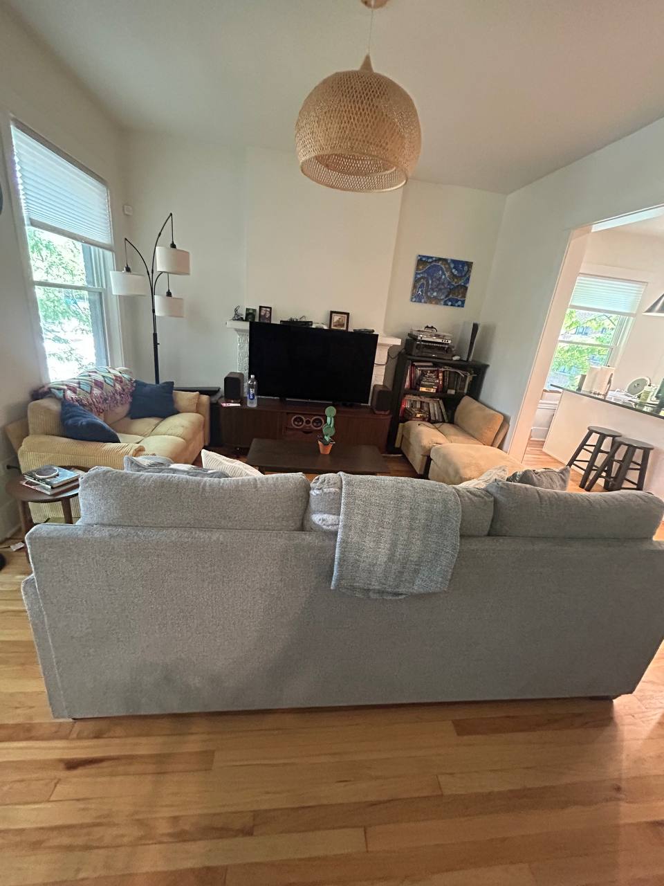 Living room with gray couch, television and woven pendant light