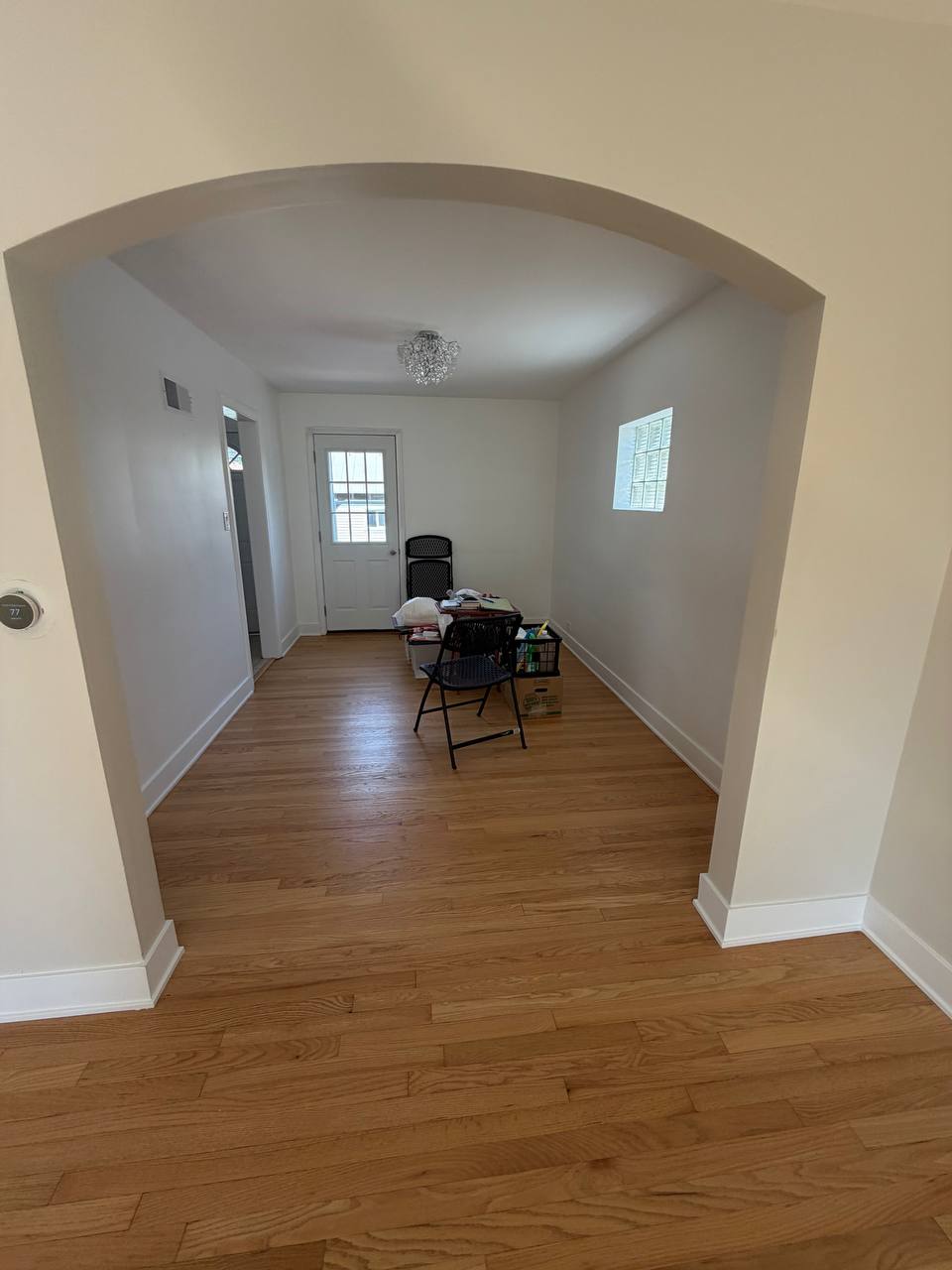 Room seen through an arch with wood floor and folding chairs