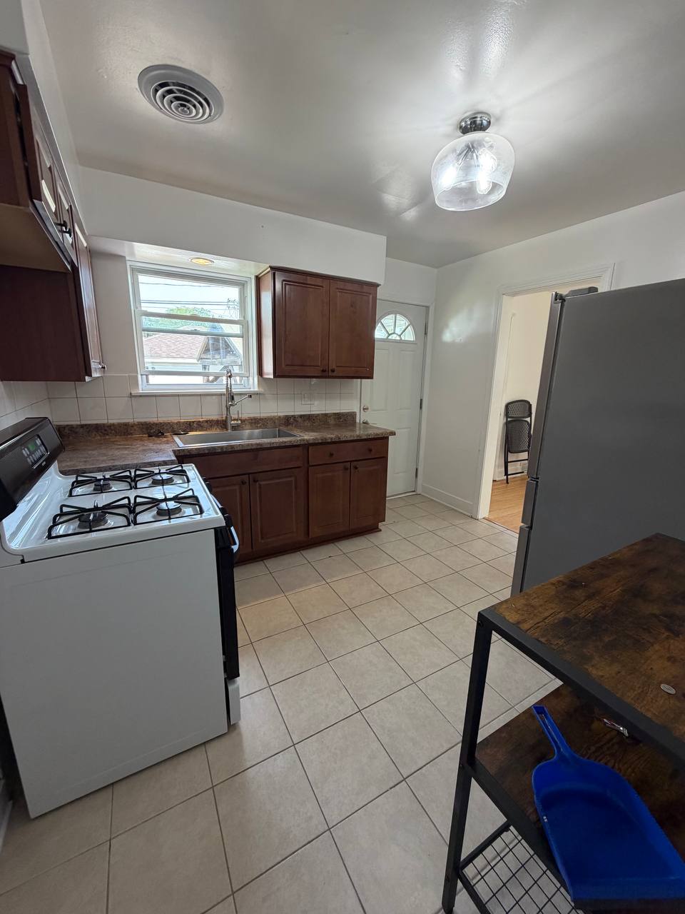 Small kitchen with dark wood cabinets, white gas stove and beige tile floor