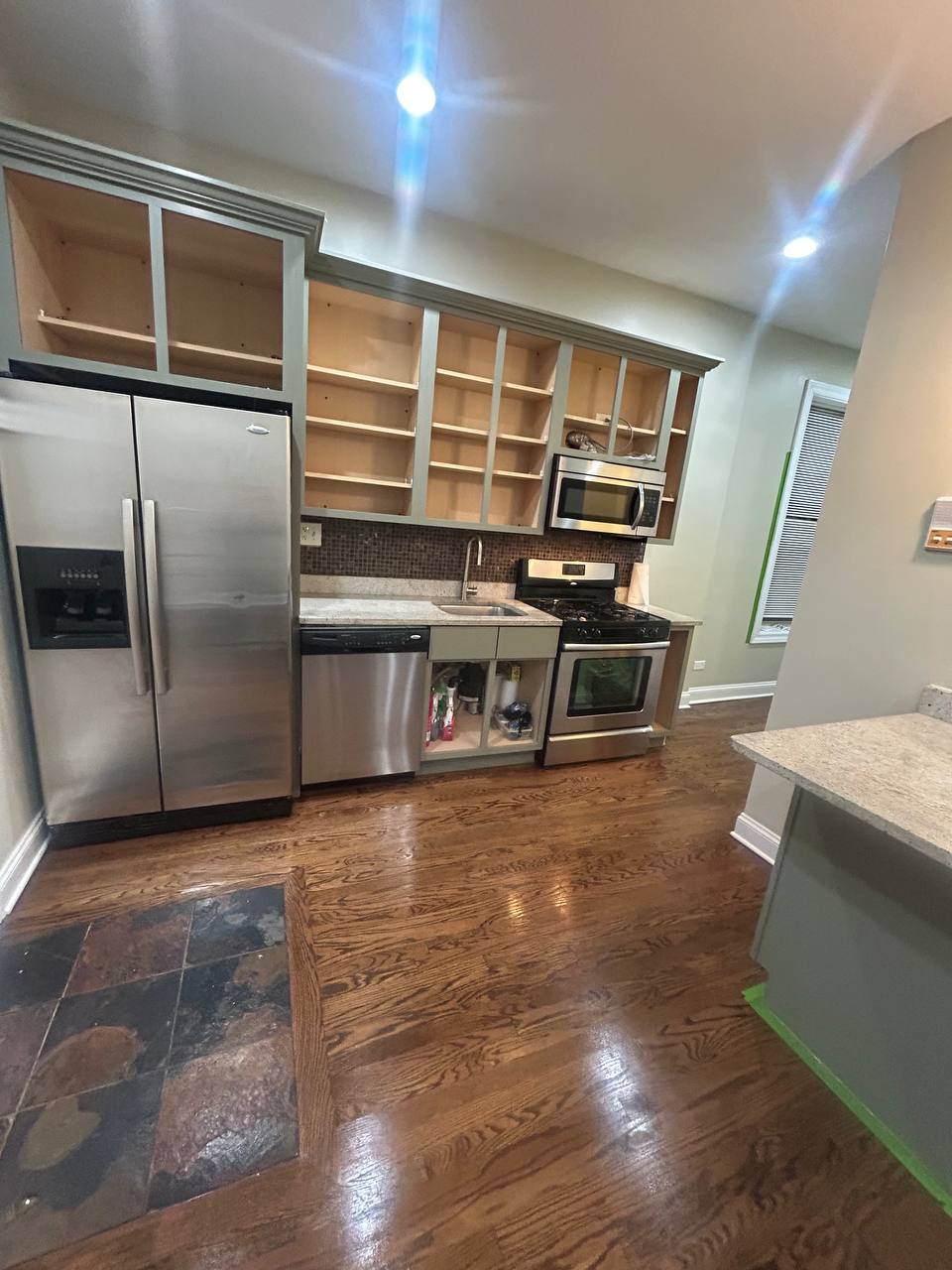 Kitchen with open gray cabinets, stainless appliances and dark wood floor