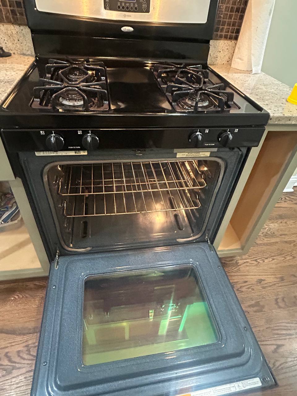 Black gas range with open oven door showing clean racks