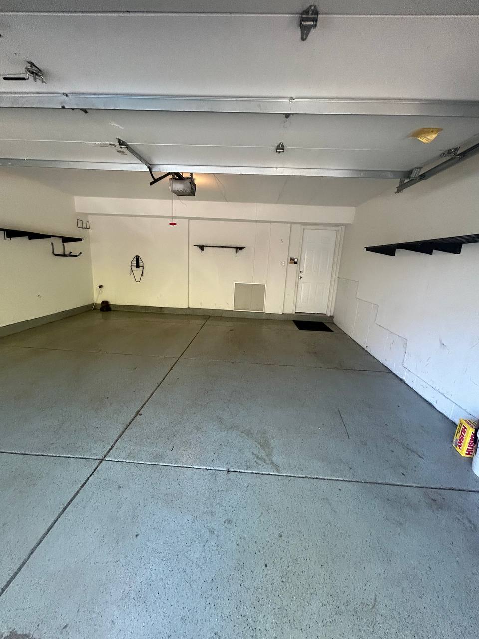 Empty two car garage with wall shelves and concrete floor
