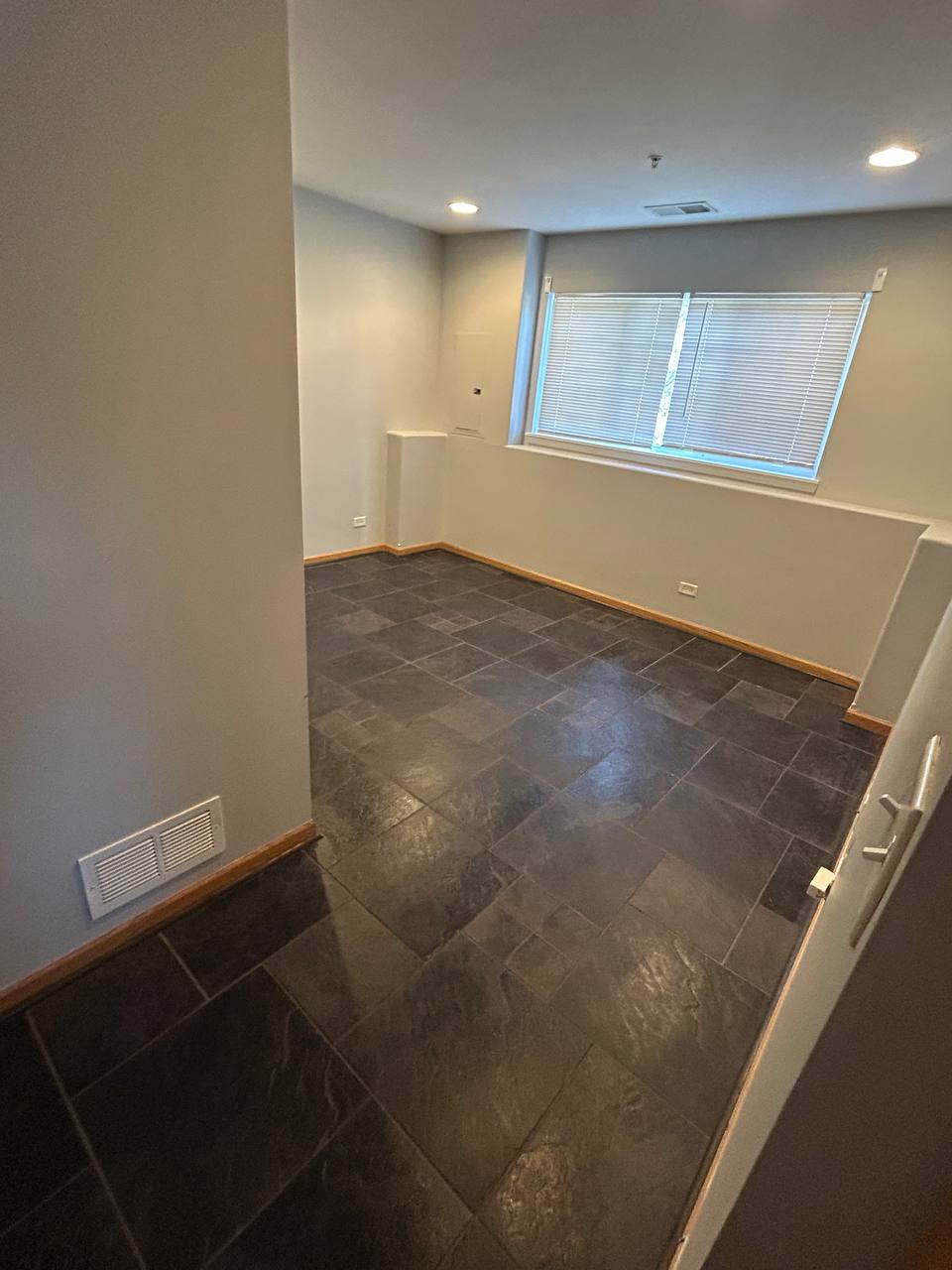 Empty room with slate tile floor, gray walls and a wide window