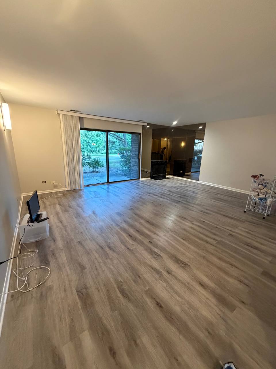 Large empty room with gray plank floor and sliding glass door