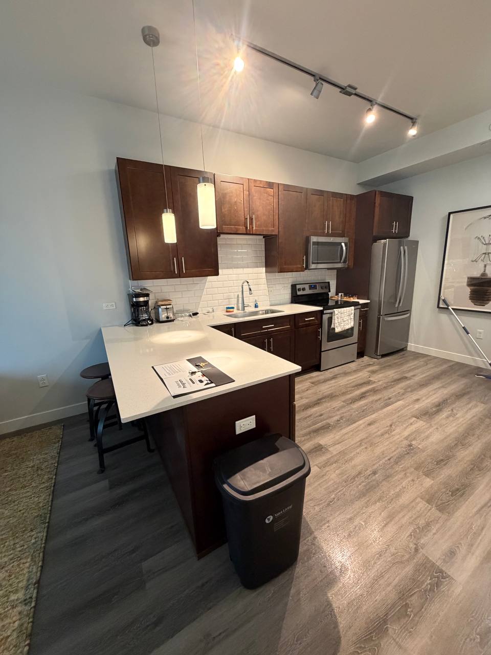 Apartment kitchen with dark cabinets, white peninsula counter and stools