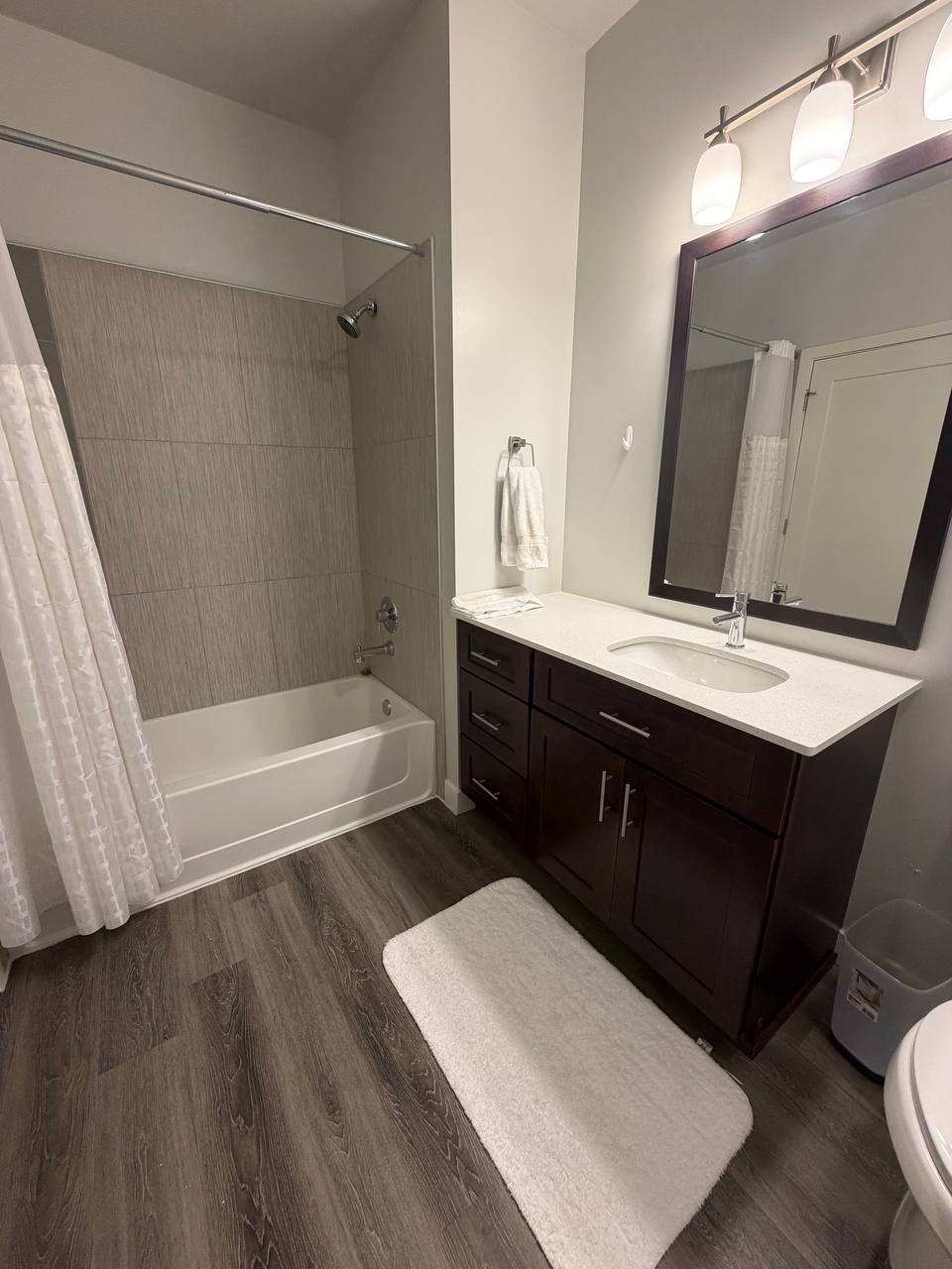 Bathroom with dark vanity, white shower curtain and bath mat