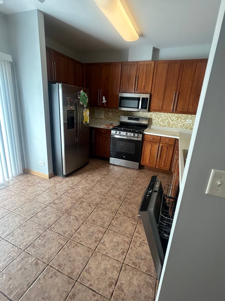 Kitchen with wood cabinets, tan tile floor and open dishwasher
