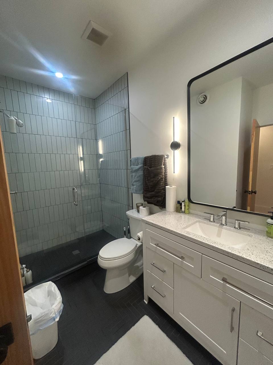 Bathroom with vertical tile walk-in shower and white vanity