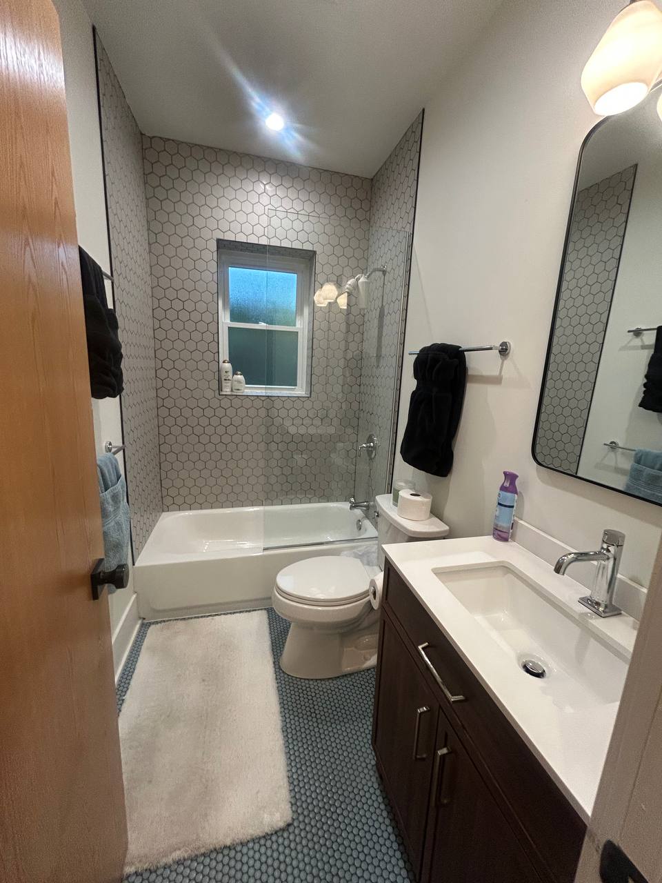 Bathroom with hexagon tile shower, tub, toilet and blue penny floor