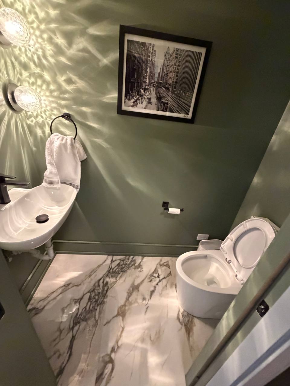 Green powder room with wall sink, toilet and marble floor