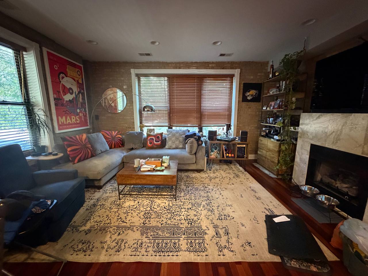 Living room with sectional sofa, patterned rug, fireplace and brick wall