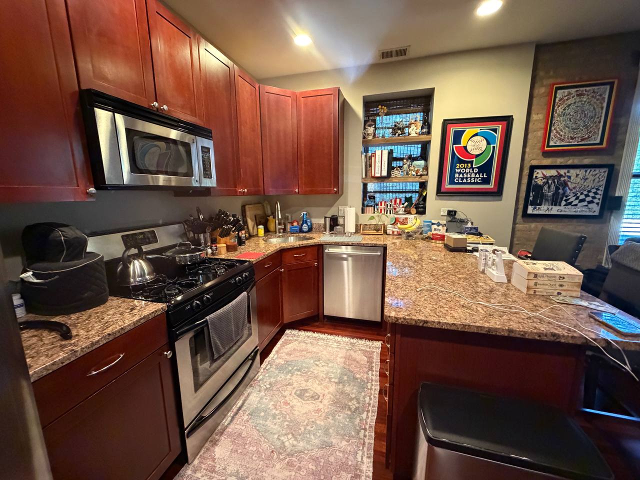 Kitchen with cherry cabinets, granite counters, stainless appliances and framed posters