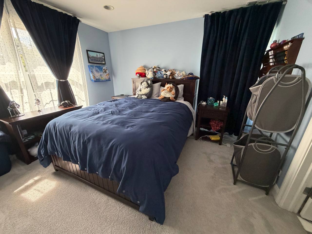 Blue bedroom with navy bedding, dark curtains and stuffed animals