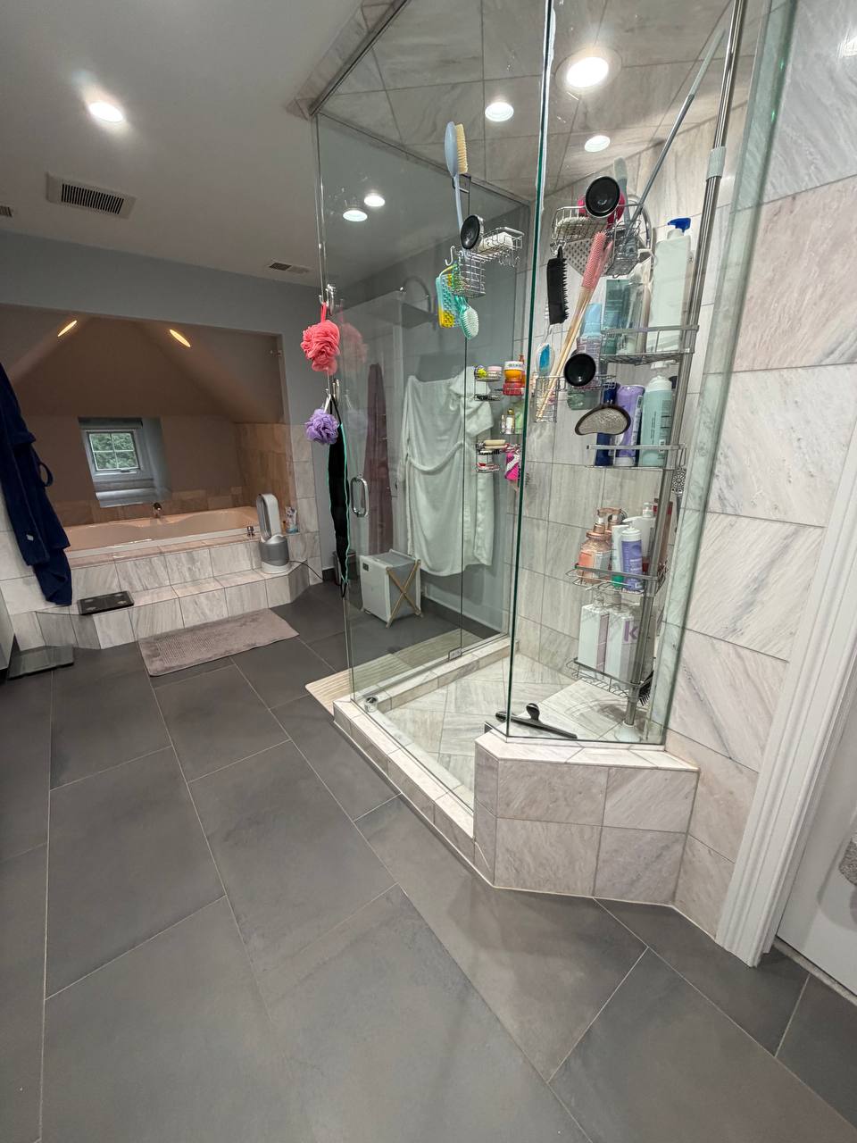 Large bathroom with glass corner shower, gray floor tile and soaking tub