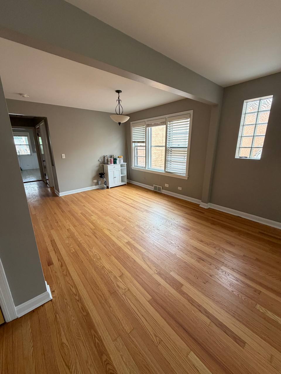 Empty dining room with light hardwood floor, gray walls and pendant
