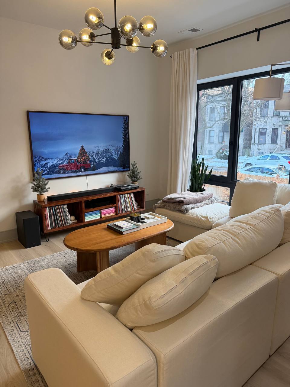 Living room with cream sectional, wood coffee table and large television