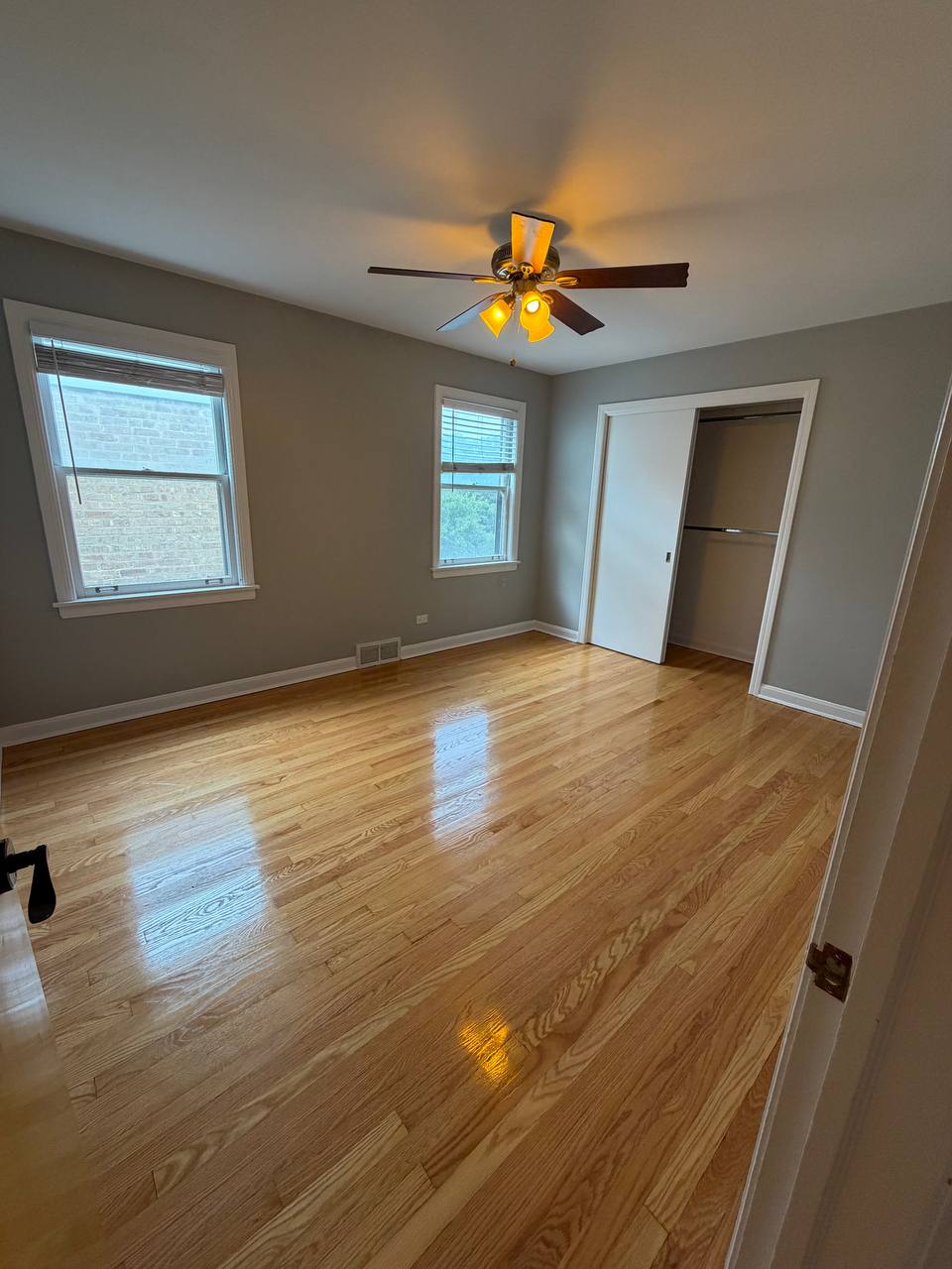 Empty bedroom with shiny hardwood floor, ceiling fan and open closet