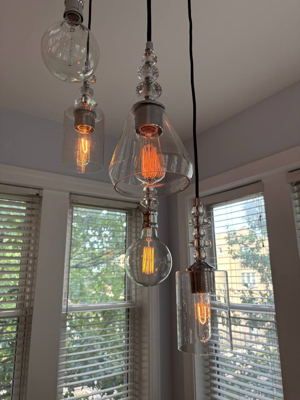 Cluster of glass pendant lights with filament bulbs by windows
