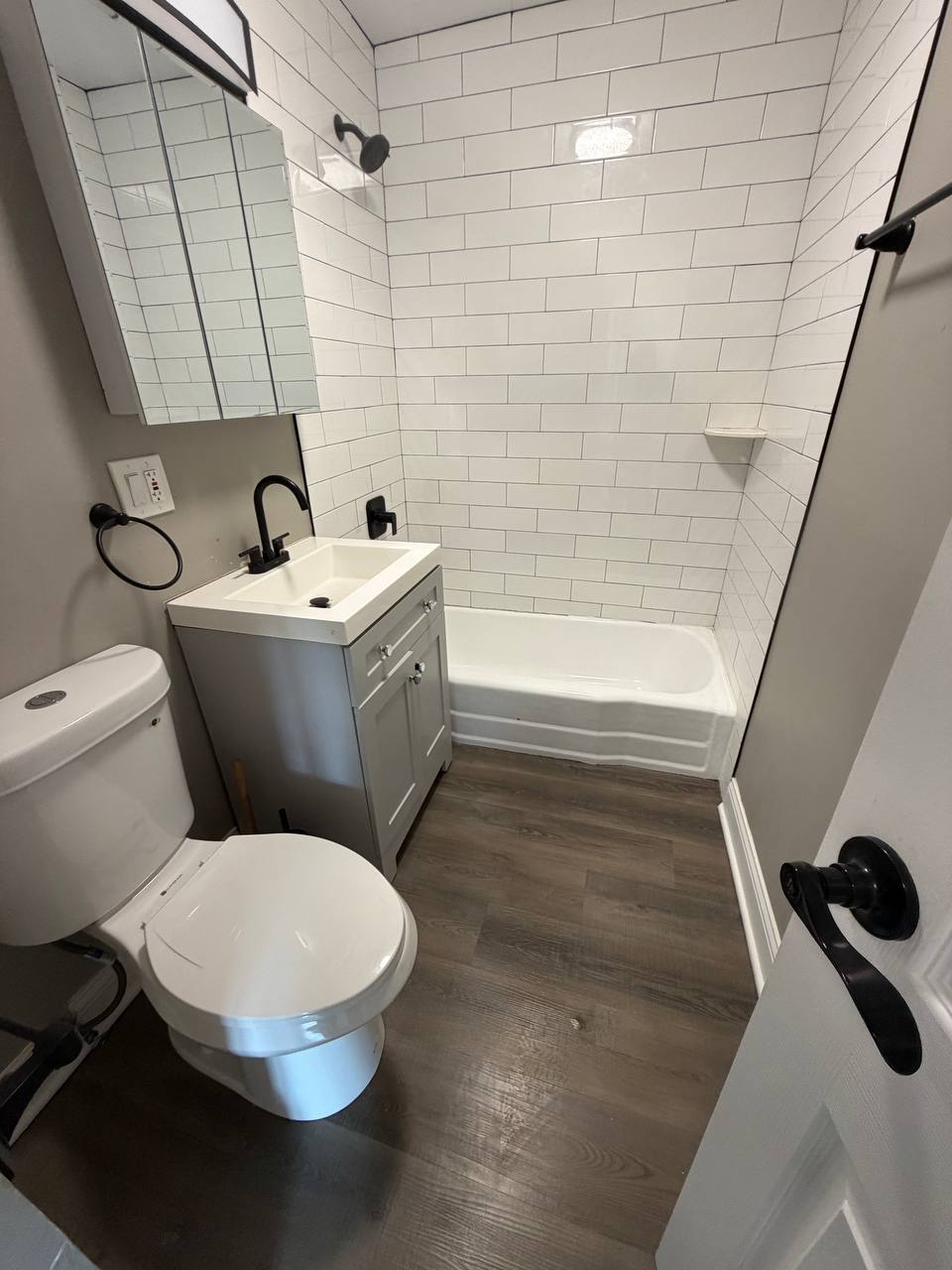 Small bathroom with white subway tile tub surround and gray vanity