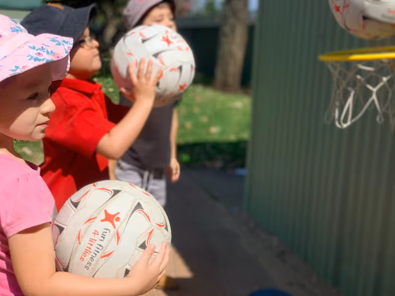 Young children holding netballs