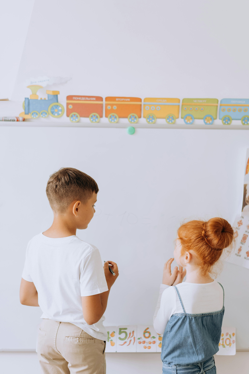 Two young children solving math problems on a whiteboard at OC Toddler School preschool in Irvine CA