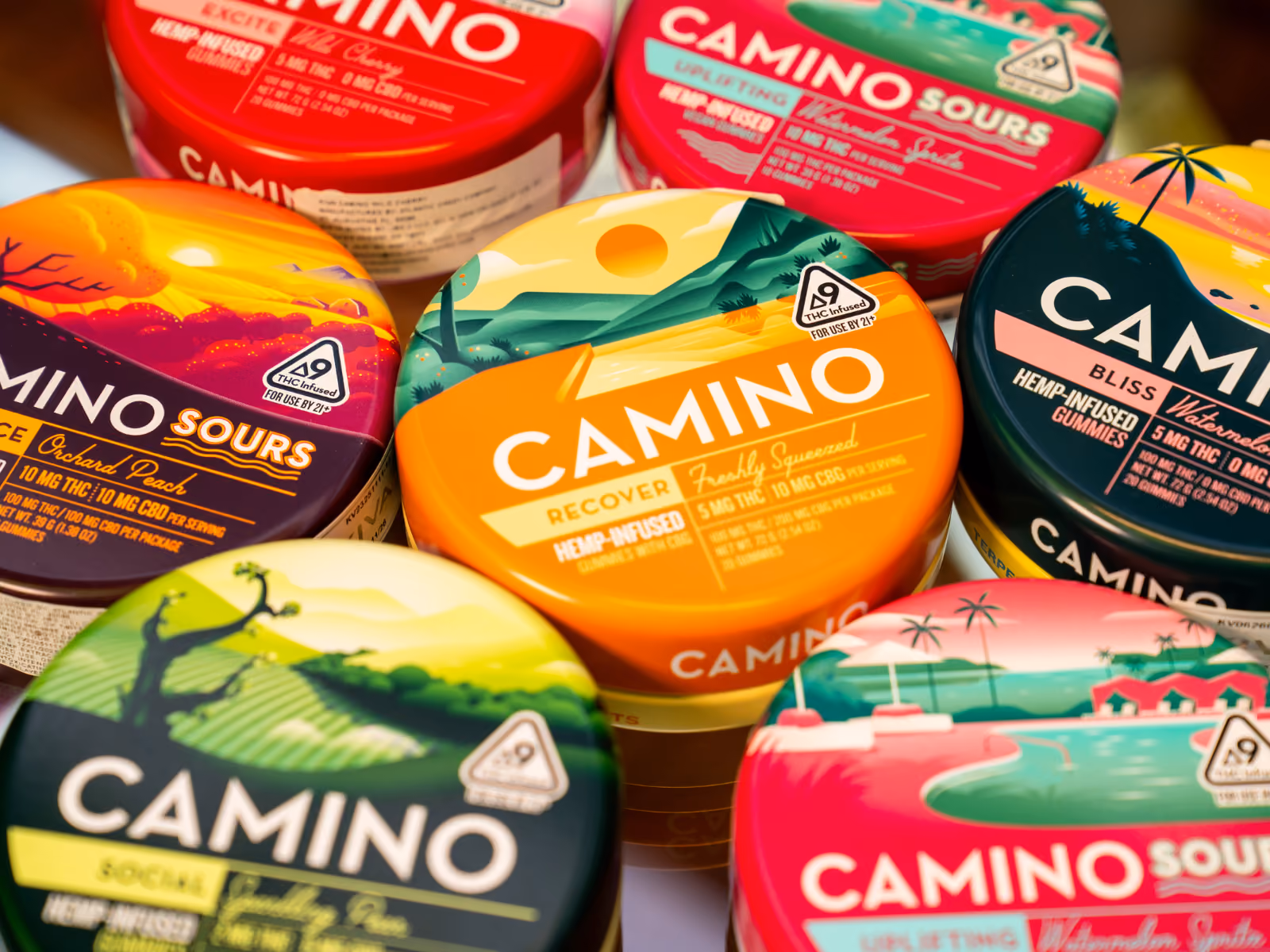 Product still of Camino hemp-infused gummy tins overlapping in bright colour, orange Recover flavour in the centre