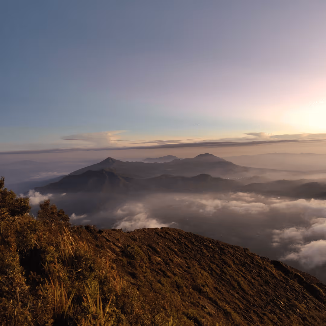 Mountainous landscape at sunrise with mist and clouds settling in the valleys.