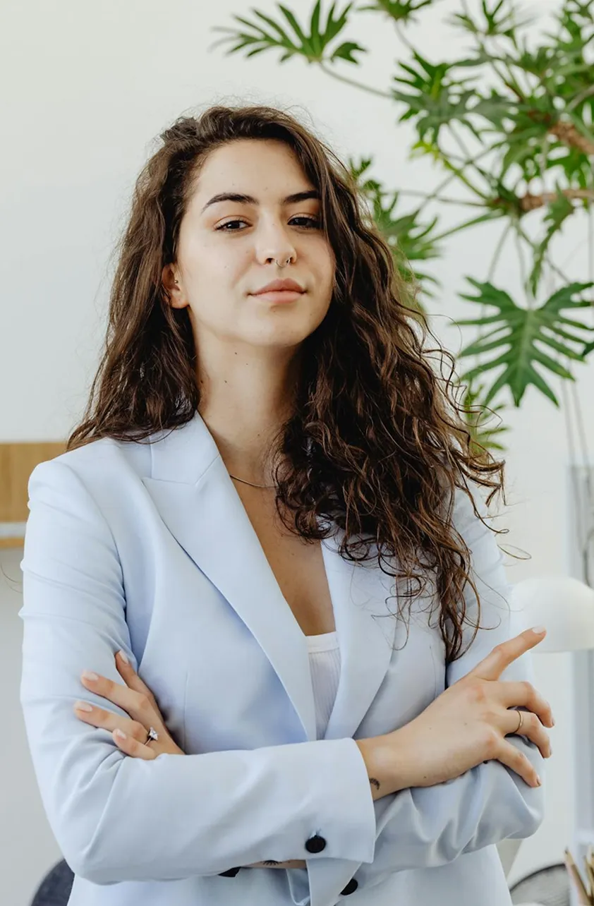 A woman in a blue suit standing with her arms crossed.