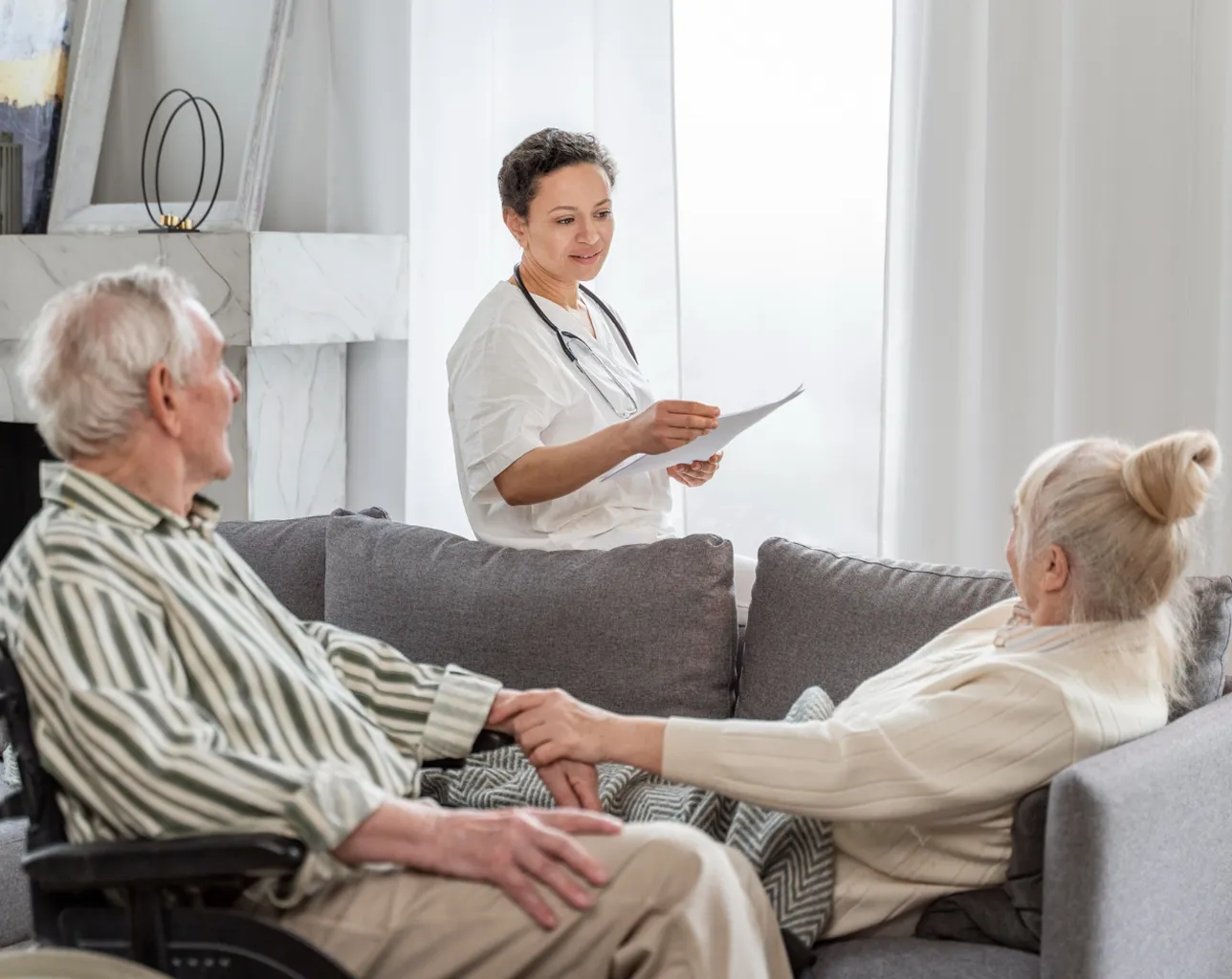 A nurse talking to a patient on a couch.