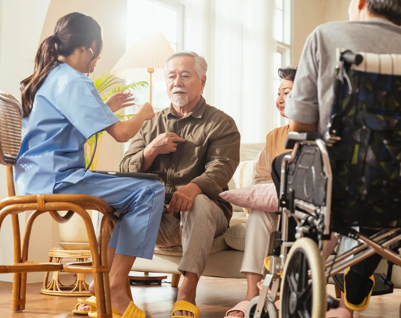 A nurse is talking to a patient in a wheelchair.