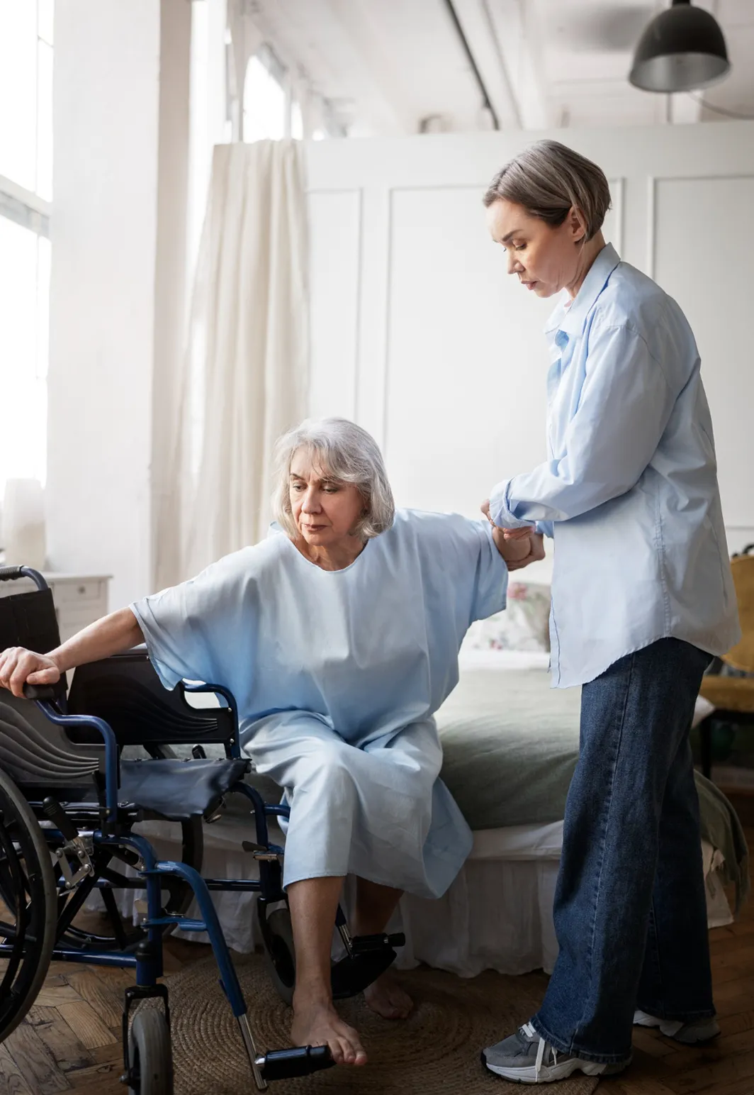 A woman in a wheelchair being assisted by a nurse.