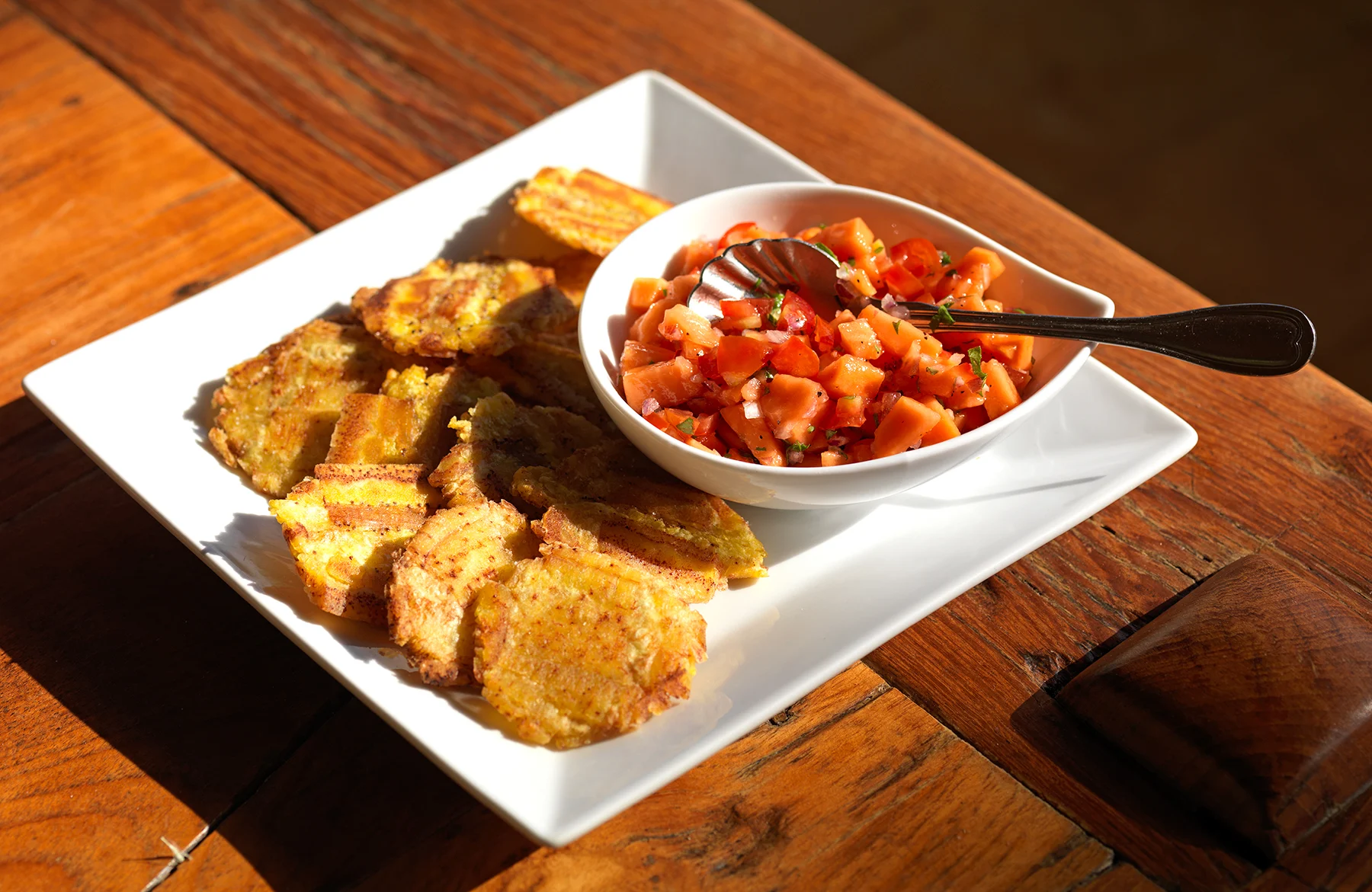 Plate of pressed fried plantain with papaya salsa