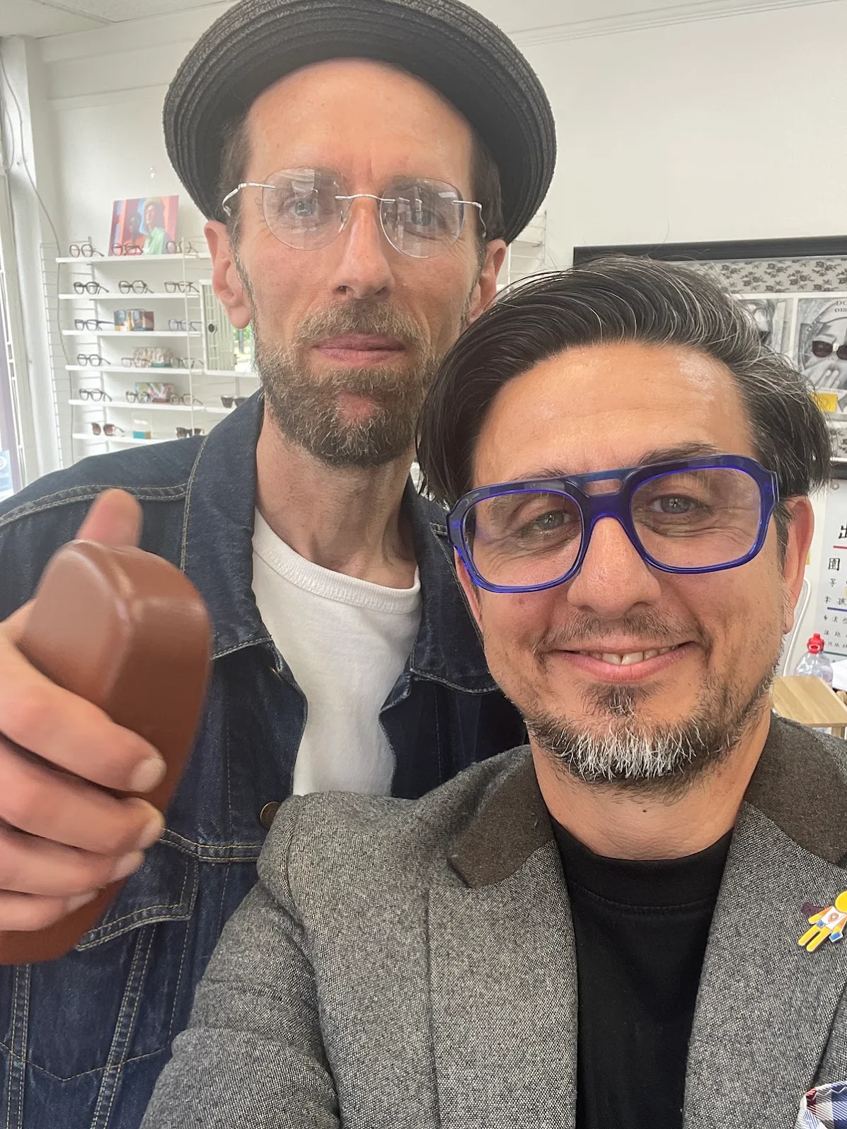Two smiling men in glasses posing together in an eyewear store