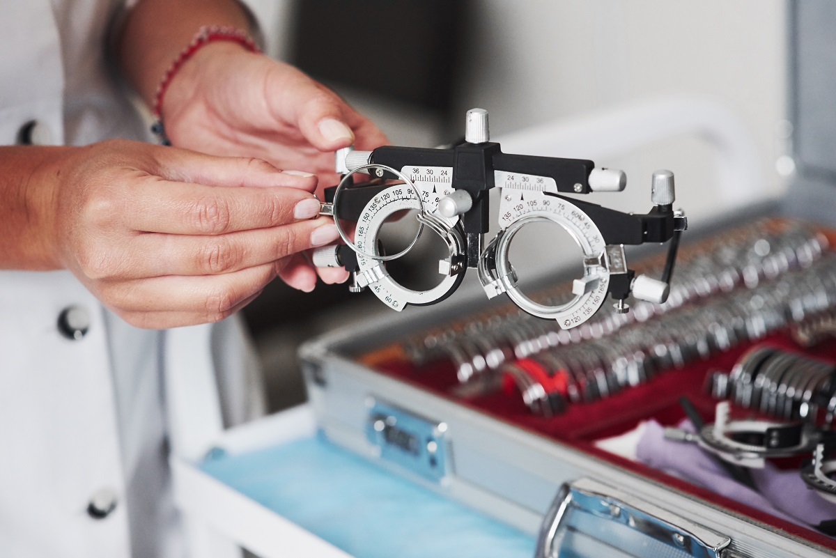 Optometrist adjusting trial frame with lens set for eye examination